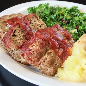 Thick slices of homestyle meatloaf topped with a savory tomato glaze, served with fluffy mashed potatoes and a fresh kale salad