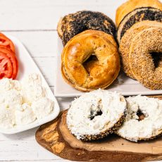 Bagels with cream cheese, sliced bagels with cream cheese and sliced tomatoes on the side.