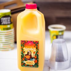 Half Gallon of Orange Juice in a plastic jug surrounded by juice cups and coffee