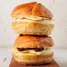 Two stacked egg and cheese sandwiches. The bottom sandwich also has bacon