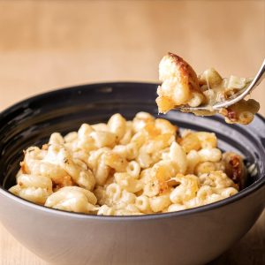 Creamy baked macaroni and cheese with a golden-brown top, with a forkful lifted to show the stretchy melted cheese